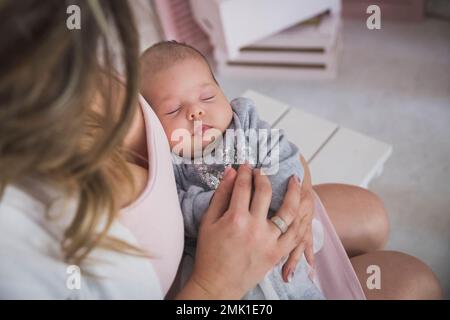 Mutter hält die schlafende, charmante, neugeborene Tochter Stockfoto