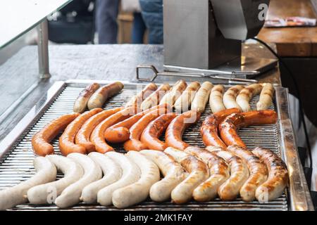 Verschiedene deutsche Würstchen auf dem Gitter eines Hot-Dog-Stalls Stockfoto