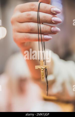 Eine Frau hält ein hölzernes Kreuz mit goldenem Kruzifix in der Hand Stockfoto