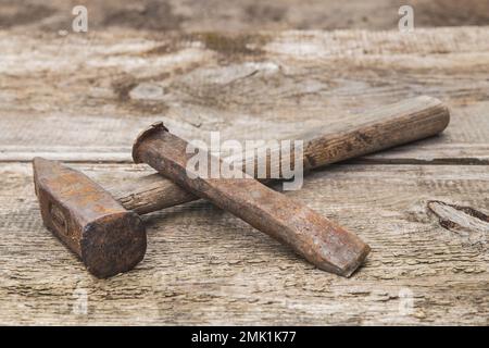 Alter Hammer und rostiger Meißel auf einer unlackierten Werkbank aus Holz Stockfoto