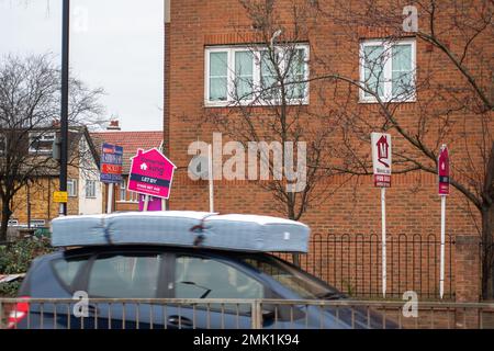 Slough, Berkshire, Großbritannien. 28. Januar 2023. Ein Auto mit einer Matratze auf dem Dach fährt vorbei an Grundstücken für Verkaufsbretter. Slough in Berkshire durchläuft einen gewaltigen Wandel. Die Gebäude werden abgerissen und sollen durch weitere Wohnungen ersetzt werden. Kredit: Maureen McLean/Alamy Live News Stockfoto