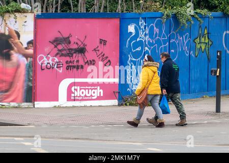 Slough, Berkshire, Großbritannien. 28. Januar 2023. Ein paar gehen an Graffiti vorbei und sagen den Leuten, sie sollen sich lieben und nett sein. Slough in Berkshire durchläuft einen gewaltigen Wandel. Die Gebäude werden abgerissen und sollen durch weitere Wohnungen ersetzt werden. Kredit: Maureen McLean/Alamy Live News Stockfoto