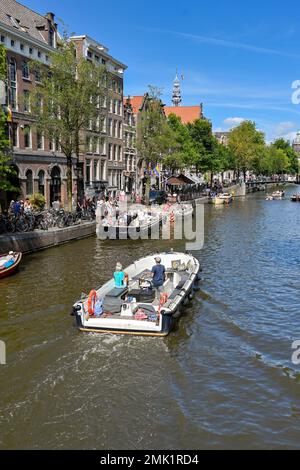 Amsterdam, Niederlande - August 2022: Malerische Aussicht auf ein Motorboot auf einem der Kanäle der Stadt Stockfoto