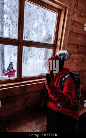 Glückliche Frau, die ihren kleinen Jungen in einer Holzhalle begrüßt, ISO Syote, Nordöstrobothnia, Lappland, Finnland Stockfoto