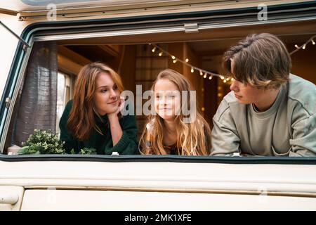 Kinder, Familie, Bruder Schwester, die im Wohnmobil reist, Haus auf Rädern. Wohnwagen Wohnwagen. Blick in Fenster. Lustige Fahrt auf der Straße. Campingbus über Nacht. Wan Stockfoto