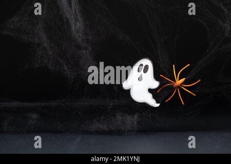 Ein erschreckender weißer Geist fliegt auf schwarzem Hintergrund mit einem Netz und einer Spinne, einer Halloween-Postkarte Stockfoto