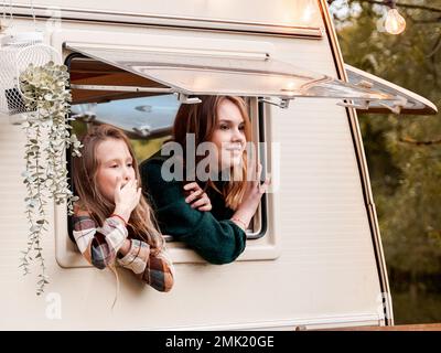 Kinder, Familie, Bruder Schwester, die im Wohnmobil reist, Haus auf Rädern. Wohnwagen Wohnwagen. Blick in Fenster. Lustige Fahrt auf der Straße. Campingbus über Nacht. Wan Stockfoto