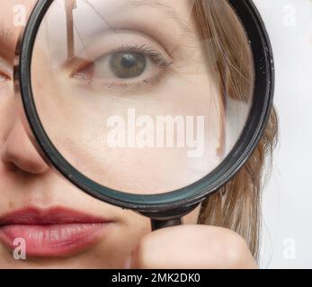 Das Auge einer erwachsenen Frau ist durch eine Lupe zu sehen. Stockfoto