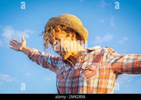Eine überfreuliche Frau, die sich im Freien die Arme ausstreckt, mit blauem Hintergrund aus dem Kopierraum. Glück und Freudengefühle. Weibliche Menschen genießen den erfolgreichen Lebensstil A. Stockfoto