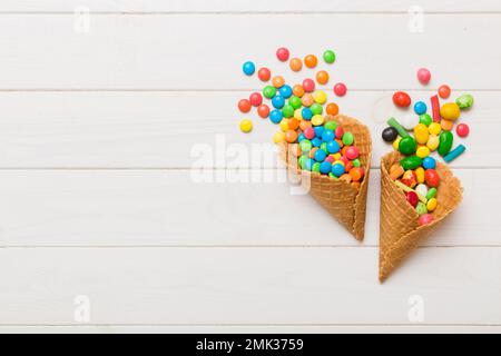 Waffelkonus voller traditioneller Süßigkeiten, die auf farbigen Hintergrund fallen, mit Platz für Kopien. Frohes Weihnachtsangebot. Stockfoto