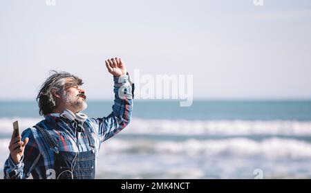 Porträt eines fröhlichen Weißen mit Hut am Strand an einem sonnigen Wintertag Stockfoto