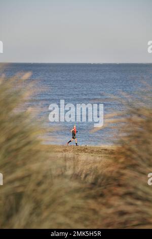 Einsamer Läufer am Strand bei Caister auf dem Meer norfolk england Stockfoto