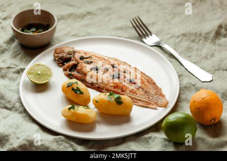 Gebratener Seezungenfisch serviert mit gekochten Kartoffeln und Petersiliensoße, Teller auf einer Serviette, Seitenansicht Stockfoto