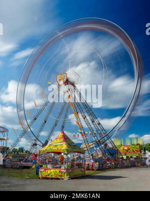 Riesenrad-Karnevalfahrt mit Bewegungsunschärfe bei langer Belichtung. Limonadenzelt im Vordergrund. Canfield Fair, Mahoning County Fair, Canfield, Youngstown, Ohi Stockfoto