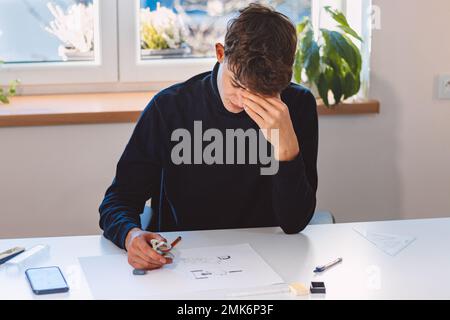 Unternehmer und Architekt denken intensiv über ein neues Design für einen neuen Prototyp nach, den er mit Bleistift auf Papier zeichnet. Ein neues Design erfinden. Ein Muster Stockfoto