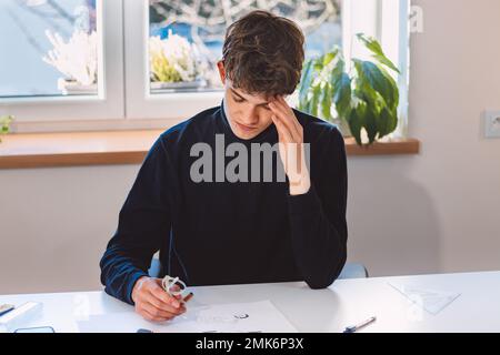 Unternehmer und Architekt denken intensiv über ein neues Design für einen neuen Prototyp nach, den er mit Bleistift auf Papier zeichnet. Ein neues Design erfinden. Ein Muster Stockfoto