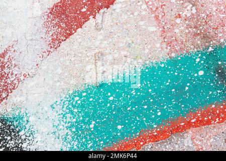 Makronahaufnahme eines Wandsprays mit weiß, rot und türkisfarbenem Anstrich. Bunte Spritzer und Spritzer. Abstrakter strukturierter Graffiti-Hintergrund. Stockfoto