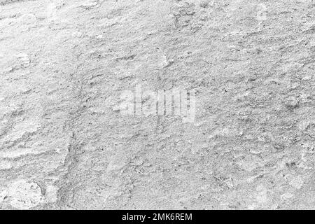 Nahaufnahme einer rauen, hellgrauen Granitfelsoberfläche, Vorderansicht. Abstrakter, natürlicher, strukturierter Vollformathintergrund in Schwarzweiß. Stockfoto