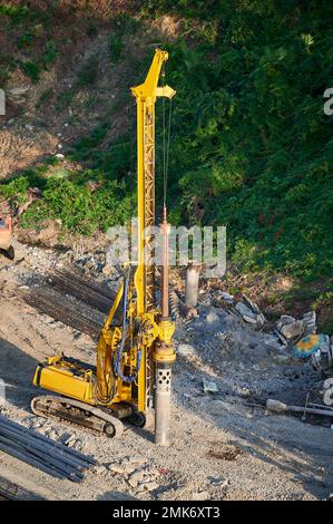 Der gelbe Pfahltreiber steuert die Fundamentpfähle auf der Baustelle. Stockfoto