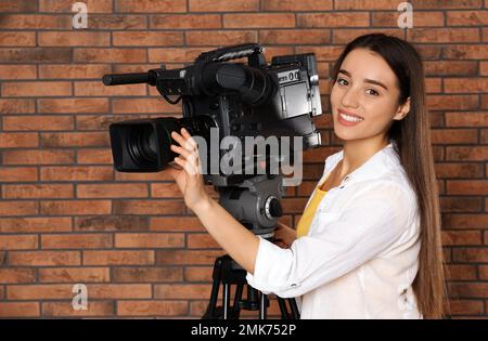 Bediener mit professioneller Videokamera in der Nähe von Ziegelmauern Stockfoto