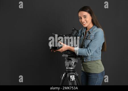 Bediener mit professioneller Videokamera auf schwarzem Hintergrund Stockfoto