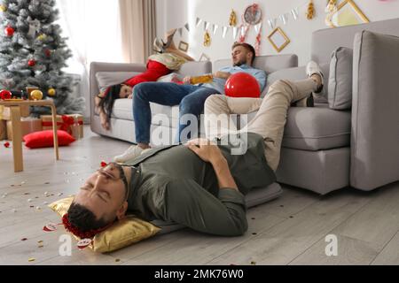 Betrunkene Freunde, die nach der Silvesterparty in einem dreckigen Zimmer schlafen Stockfoto