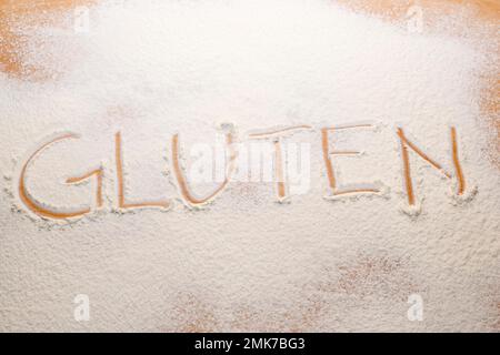Das Wort Gluten stand im Mehl auf einem Nudelbrett Stockfoto
