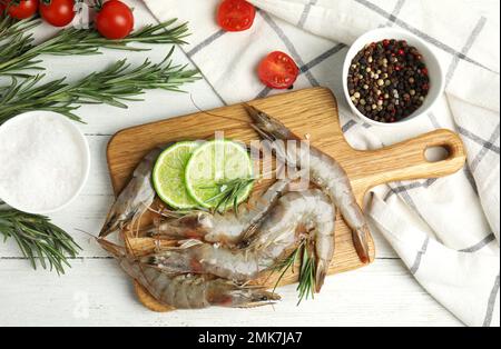 Flache Liegezusammensetzung mit rohen Garnelen auf weißem Holztisch Stockfoto