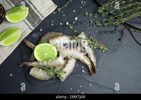 Flache Laienzusammensetzung mit rohen Garnelen auf schwarzem Tisch Stockfoto