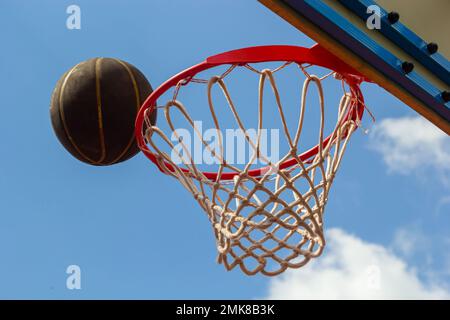 Ein Basketball im Netz. Die Fliege ist im Ring. Ein Sportspiel. Konzeptionell: Sieg, Erfolg, Zielerreichungen, Sport. Erfolgreicher Ballwurf. Stockfoto