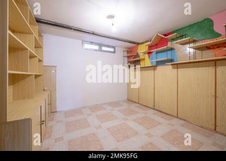 Leerer Raum mit eingebautem Kleiderschrank und Bücherregal aus demselben Material, kleinen Fenstern und Steinzeug-Fußböden Stockfoto