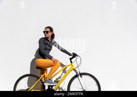 Eine Frau, die mit dem Fahrrad über ihre Schulter schaut, weißer Hintergrund mit Werbeträger. Stockfoto