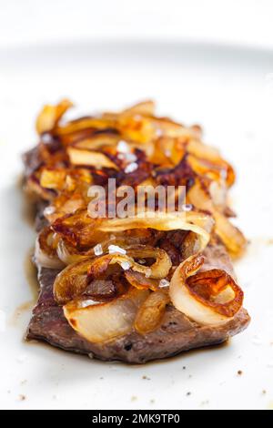 Steak mit karamellisierten Zwiebeln bedeckt Stockfoto