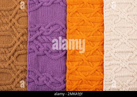 Gestrickter Hintergrund in Beige, Lila, Braun und Orange. Großer Strickstoff mit Muster. Nahaufnahme einer Strickdecke. Stockfoto