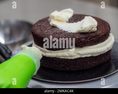 Der Chefkoch, der Gebäck designt, konfektioniert einen mit Erdbeeren, Blaubeeren und Schlagsahne gefüllten Kuchen im 3. Stock. Kuchenstruktur bef Stockfoto