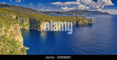 Blick auf die steilen Klippen und das ruhige blaue Meer in Waterfall Bay, Tasman-Nationalpark, Tasmanien, Australien Stockfoto