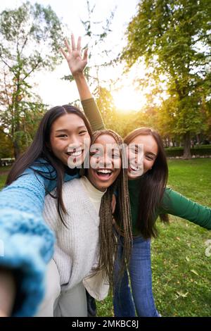 Vertikales Porträt von drei Mädchen außerhalb, die Selfie-Freundschaft in multiethnischen Gruppen aufnehmen Stockfoto