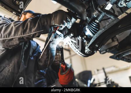 Mechaniker, die Autoräder mit verschiedenen modernen Werkzeugen in einer Kfz-Reparaturstation ersetzen. Hochwertige Fotos Stockfoto