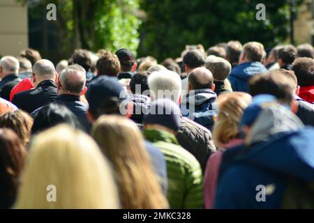 Die Menge nimmt an einem politischen Treffen Teil. Eine große Gruppe von Menschen als Zuschauer für die Rede eines Politikers im Freien auf der Großleinwand. Stockfoto