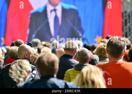 Die Menge nimmt an einem politischen Treffen Teil. Eine große Gruppe von Menschen als Zuschauer für die Rede eines Politikers im Freien auf der Großleinwand. Stockfoto