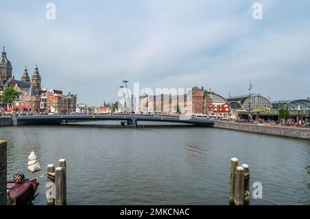 AMSTERDAM, NIEDERLANDE - 24. AUGUST 2013: Blick auf Amsterdam mit Fluss und Booten, in der Nähe des Hauptbahnhofs Stockfoto