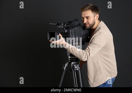 Bediener mit professioneller Videokamera auf schwarzem Hintergrund Stockfoto