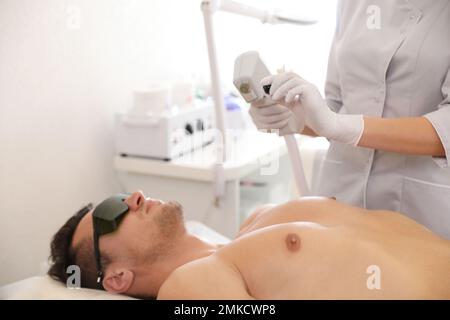 Junger Mann, der sich im Schönheitssalon einem Laser-Epilierverfahren unterzogen hat Stockfoto