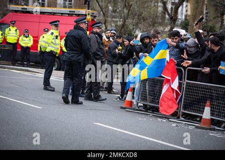 Die Metropolitan Police steht Wache, während die Demonstranten sich darauf vorbereiten, die schwedischen und dänischen Flaggen während der Demonstration gegen die Verbrennung von Koran in Schweden zu verbrennen. Der hohe Vertreter der Allianz der Zivilisationen der Vereinten Nationen hat die Verbrennung des heiligen muslimischen Buches durch einen schwedisch-dänischen rechtsextremen Politiker als "abscheulichen Akt" verurteilt. Rasmus Paludan, Anführer der dänischen rechtsextremen politischen Partei Hard Line, führte am Freitag, den 27. Januar 2023 unter dem Schutz der örtlichen Polizei vor der türkischen Botschaft in Schweden die Aktion durch. Stockfoto