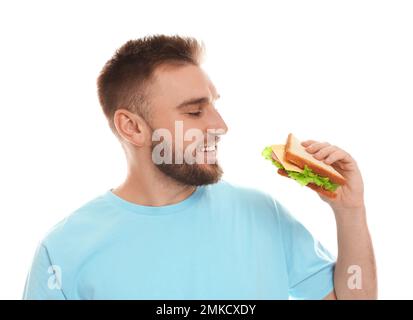 Junger Mann, der leckeres Sandwich auf weißem Hintergrund isst Stockfoto