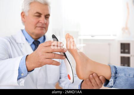 Die Einlegesohle des männlichen Orthopäden am Fuss des Patienten in der Klinik Stockfoto