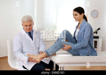 Die Einlegesohle des männlichen Orthopäden am Fuss des Patienten in der Klinik Stockfoto
