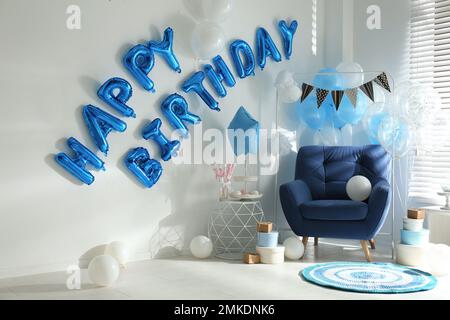 Phrase HAPPY BIRTHDAY aus blauen Ballonbuchstaben im dekorierten Zimmer Stockfoto