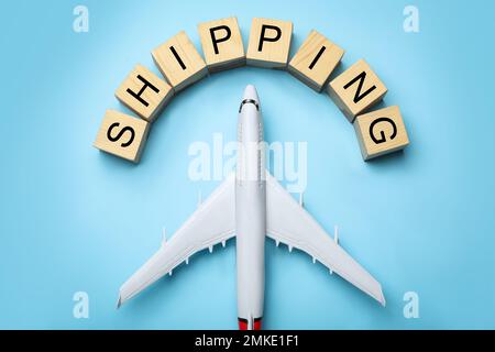 Spielzeugflugzeug mit WORTVERSAND auf blauem Hintergrund, flach liegend. Logistik- und Großhandelskonzept Stockfoto