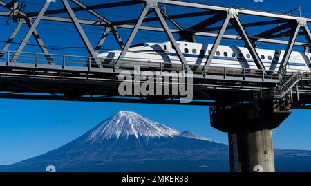 Ein Zug der JR Central N700S der Tokaido Shinkansen Line überquert eine Brücke über den Fuji River (Fujikawa), wobei der Fuji in der Präfektur Shizuoka zu sehen ist Stockfoto